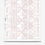 Partially unrolled wallpaper yardage in a watercolor dyed grid print in mottled white and pink.