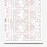 Partially unrolled wallpaper yardage in a watercolor dyed grid print in mottled white and pink.