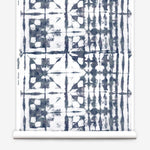 Partially unrolled wallpaper yardage in a watercolor dyed grid print in mottled white and navy.