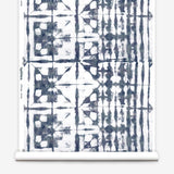 Partially unrolled wallpaper yardage in a watercolor dyed grid print in mottled white and navy.