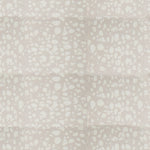Detail of fabric in a batik splatter print in cream on a light gray field.