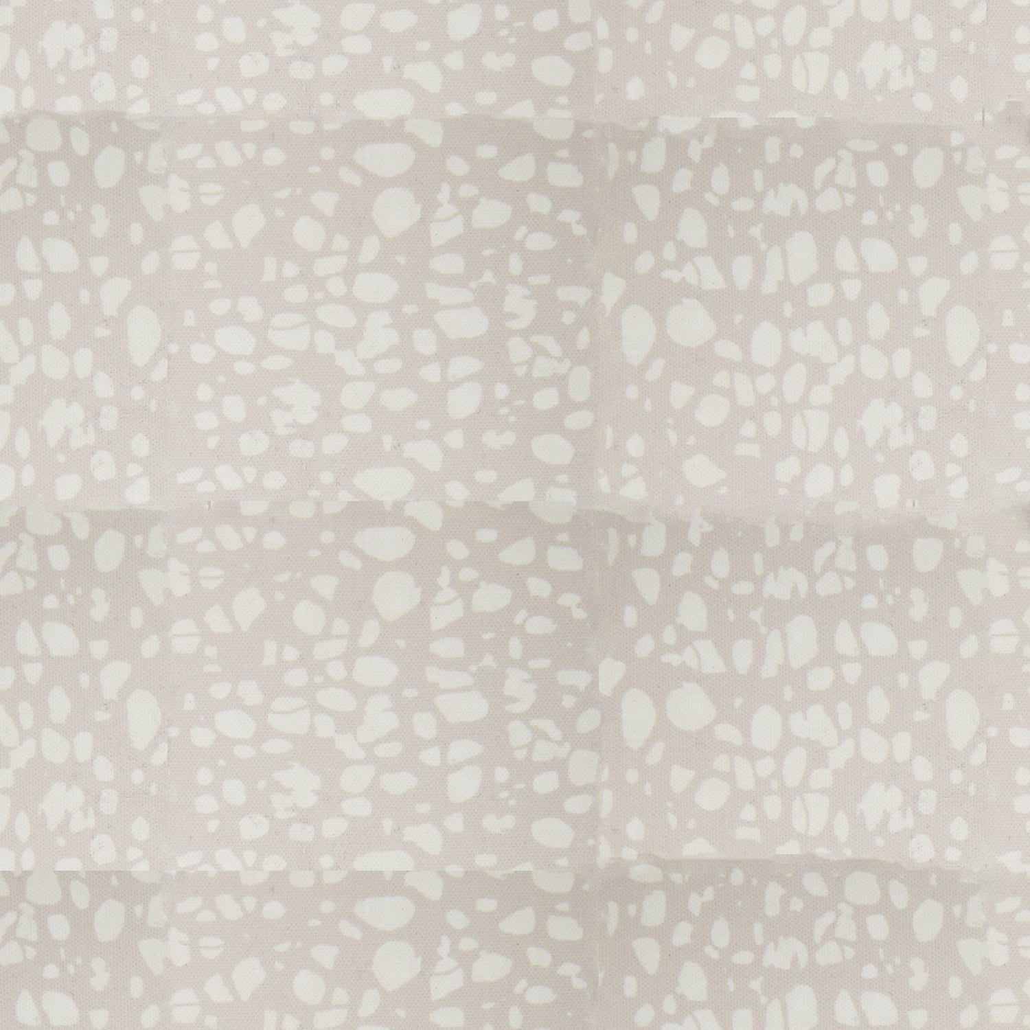 Detail of fabric in a batik splatter print in cream on a light gray field.