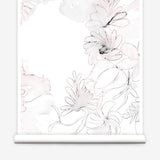 Partially unrolled wallpaper yardage in a painterly floral print in shades of pink and charcoal on a white field.