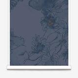 Partially unrolled wallpaper yardage in a painterly floral print in shades of navy and tan on a blue field.