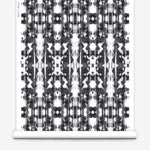Partially unrolled wallpaper yardage in a painterly ikat print in black on a white field.