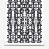 Partially unrolled wallpaper yardage in a painterly ikat print in black on a white field.