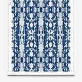 Partially unrolled wallpaper yardage in a painterly ikat print in blue and white.