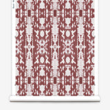 Partially unrolled wallpaper yardage in a painterly ikat print in rust and white.