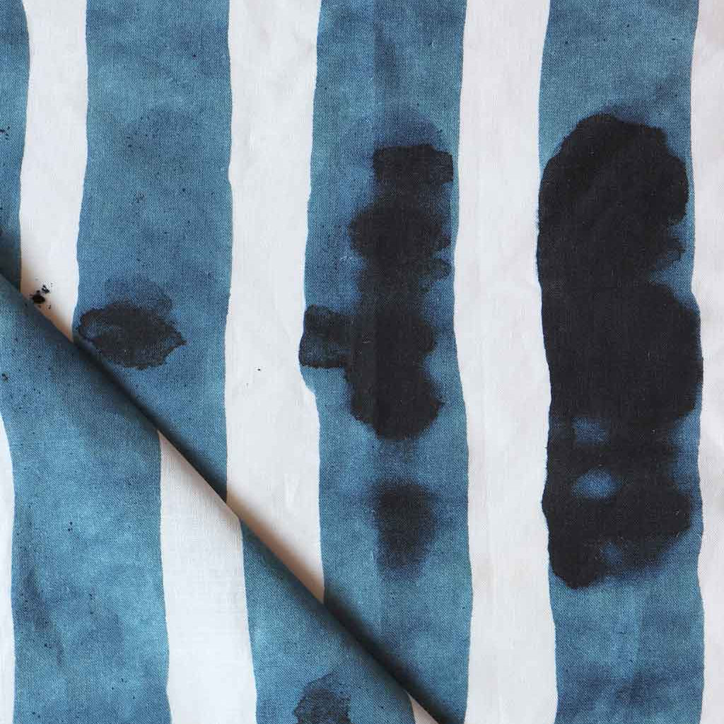Folded printed linen with bold watercolor stripes in inky blue and white. 