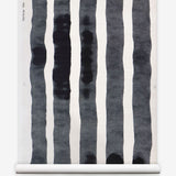 Grasscloth Wallpaper roll with bold watercolor stripes in black and white on a white background. 