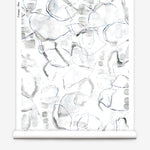 Partially unrolled wallpaper yardage in a watercolor painterly print in shades of gray, purple and cream.