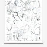 Partially unrolled wallpaper yardage in a watercolor painterly print in shades of gray, purple and cream.