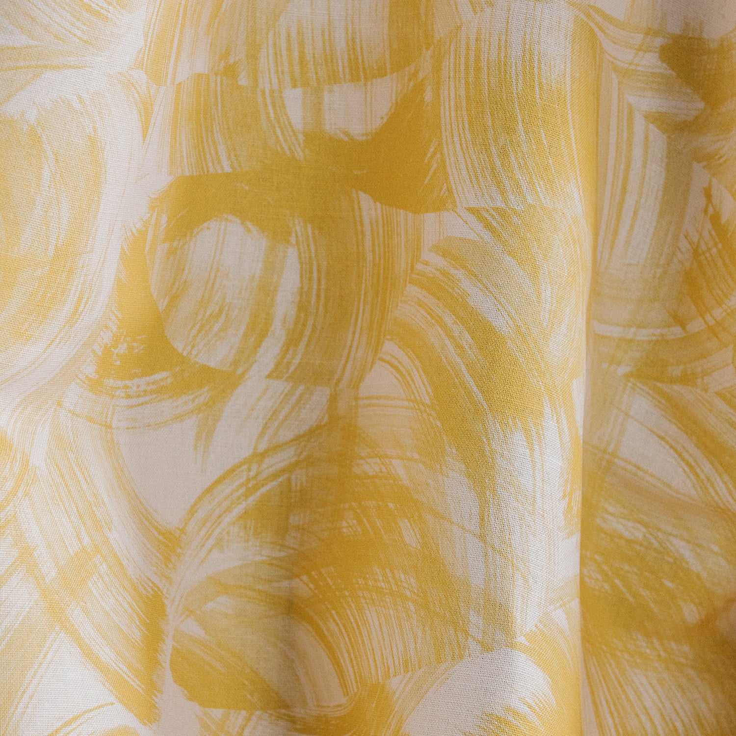 Draped fabric yardage in an absract paint swatch print in yellow on a white field.
