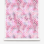 Partially unrolled wallpaper yardage in a painterly chess board print in pink, purple and white.