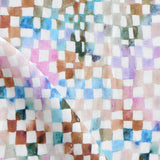 Detail of fabric in a painterly check pattern in shades of pink, brown and blue on a white field.