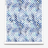 Partially unrolled wallpaper yardage in a painterly chess board print in shades of blue, navy and white.