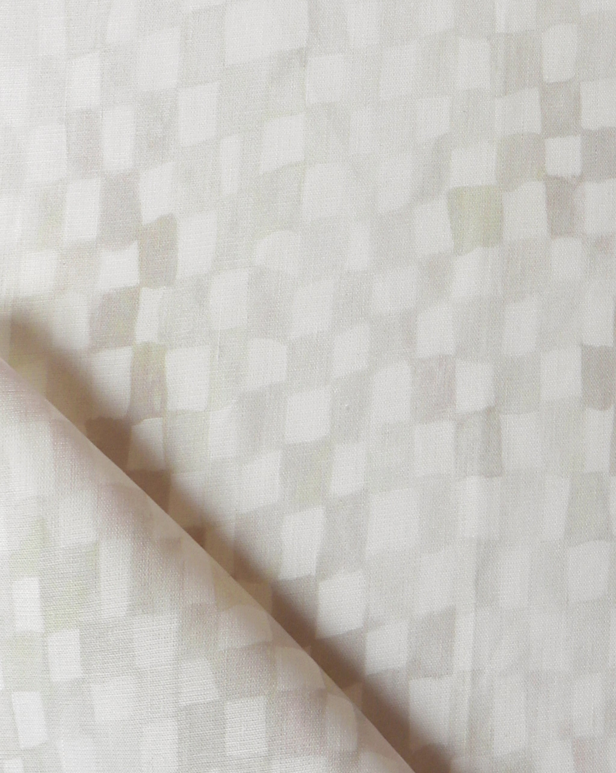 Detail of fabric in a painterly check pattern in cream on a white field.