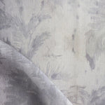 Detail of fabric in a painterly palm leaf print in shades of purple on a greige field.
