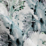 Detail of fabric in a painterly palm leaf print in shades of green, turquoise and gray on a cream field.