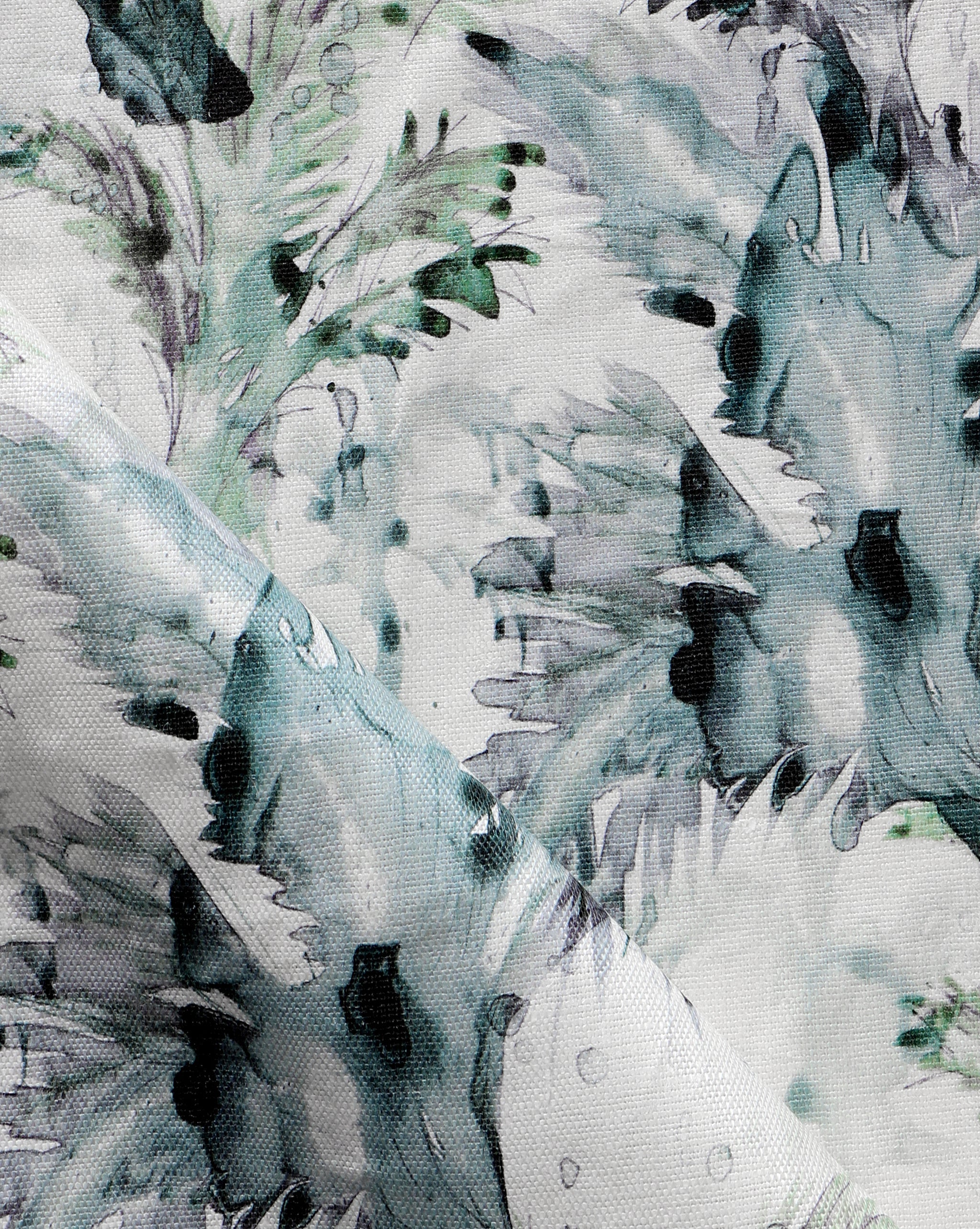 Detail of fabric in a painterly palm leaf print in shades of green, turquoise and gray on a cream field.