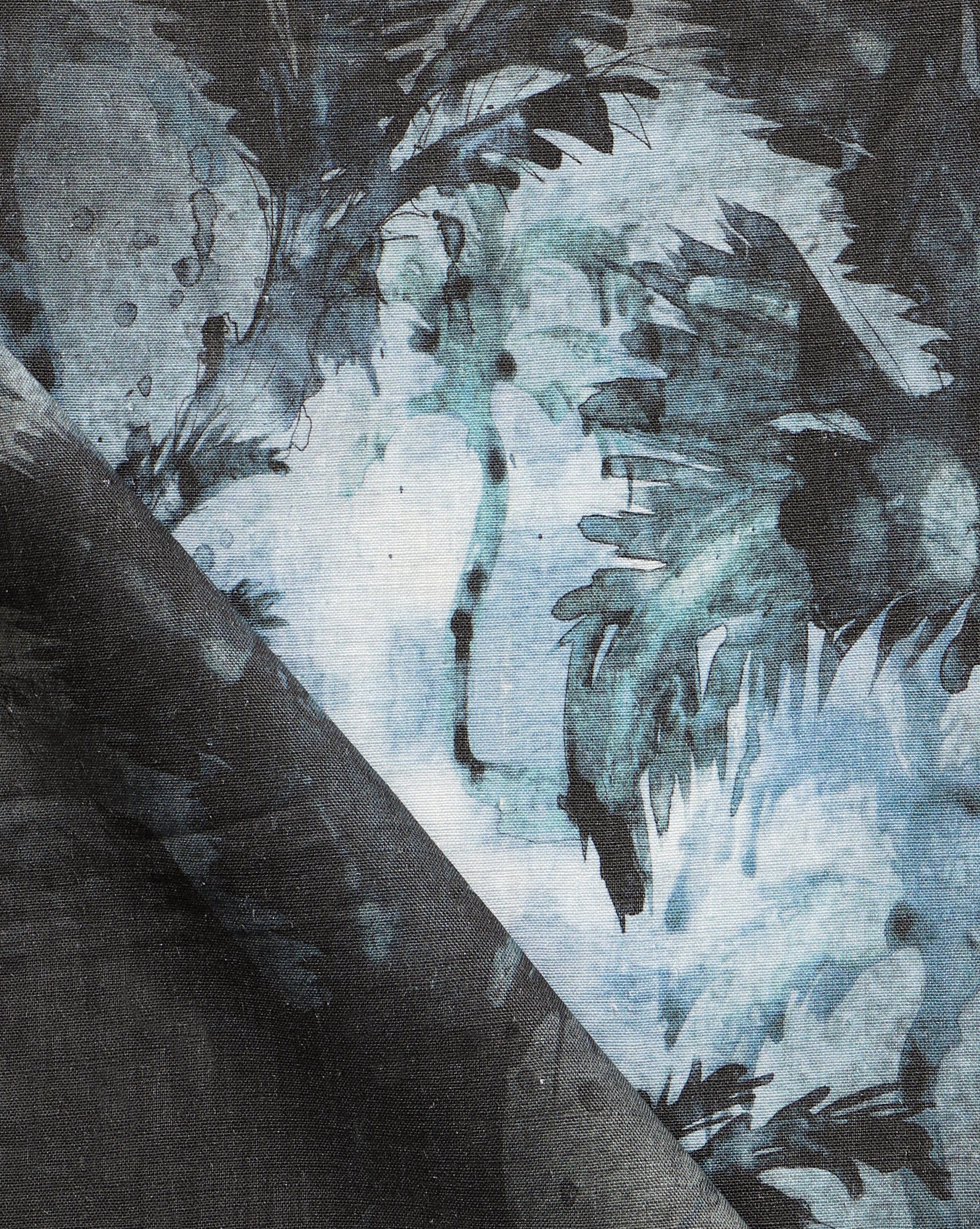 Detail of fabric in a painterly palm leaf print in shades of gray and turquoise on a cream field.