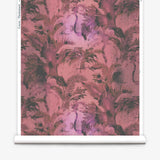 Partially unrolled wallpaper yardage in a painterly palm tree print in shades of red, pink and gray.