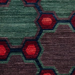 Close-up of a geometric patterned rug with red, green, and brown colors.