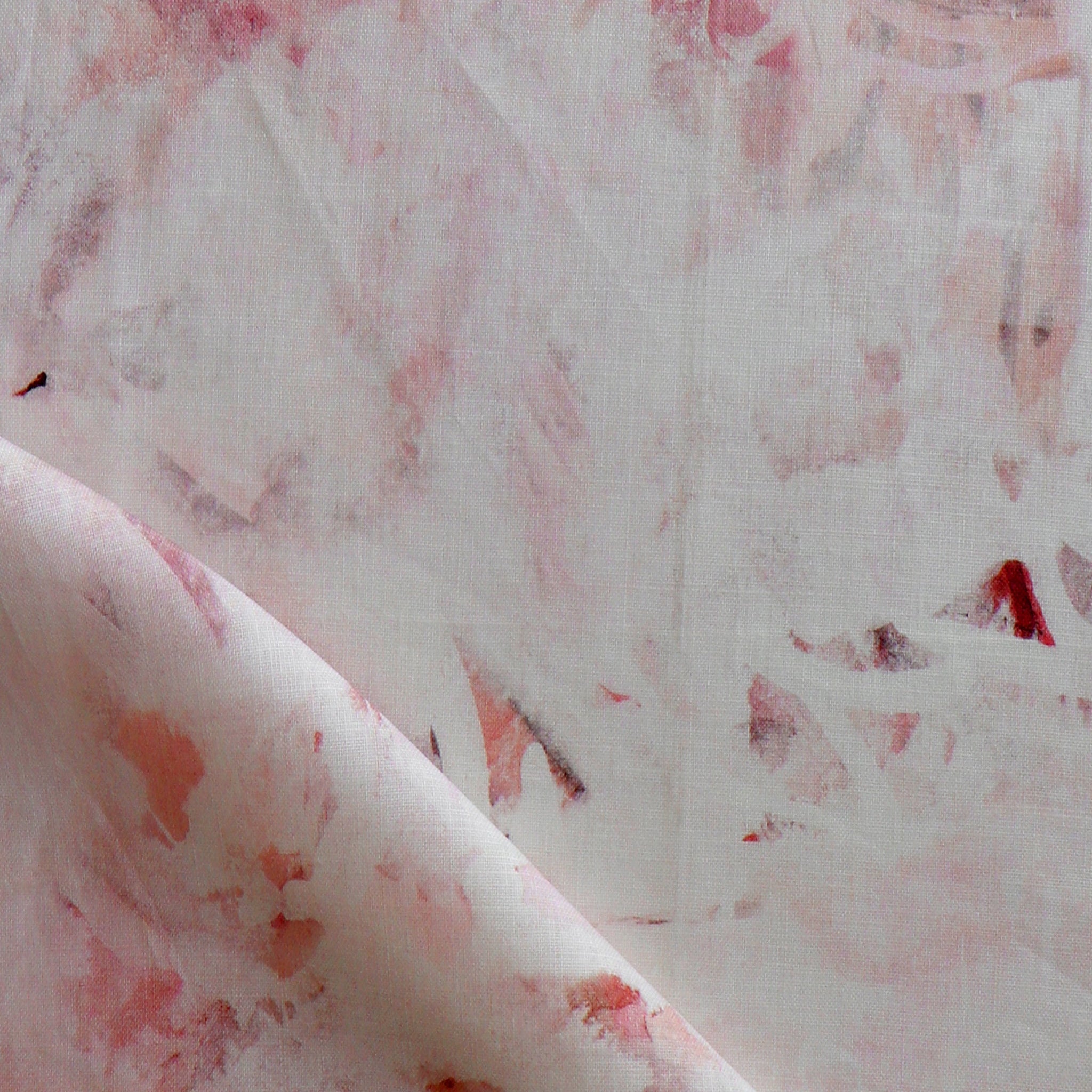 Detail of fabric in a watercolor painterly print in pink and red on a cream field.