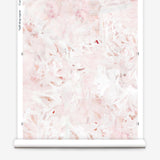 Partially unrolled wallpaper yardage in a watercolor painted print in shades of pink, red and white.