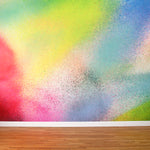 A wall mural in an abstract ombré paint splatter print in shades of pink, yellow, blue and green.