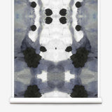 Partially unrolled wallpaper yardage in a watercolor ink blot print in charcoal, gray and white.