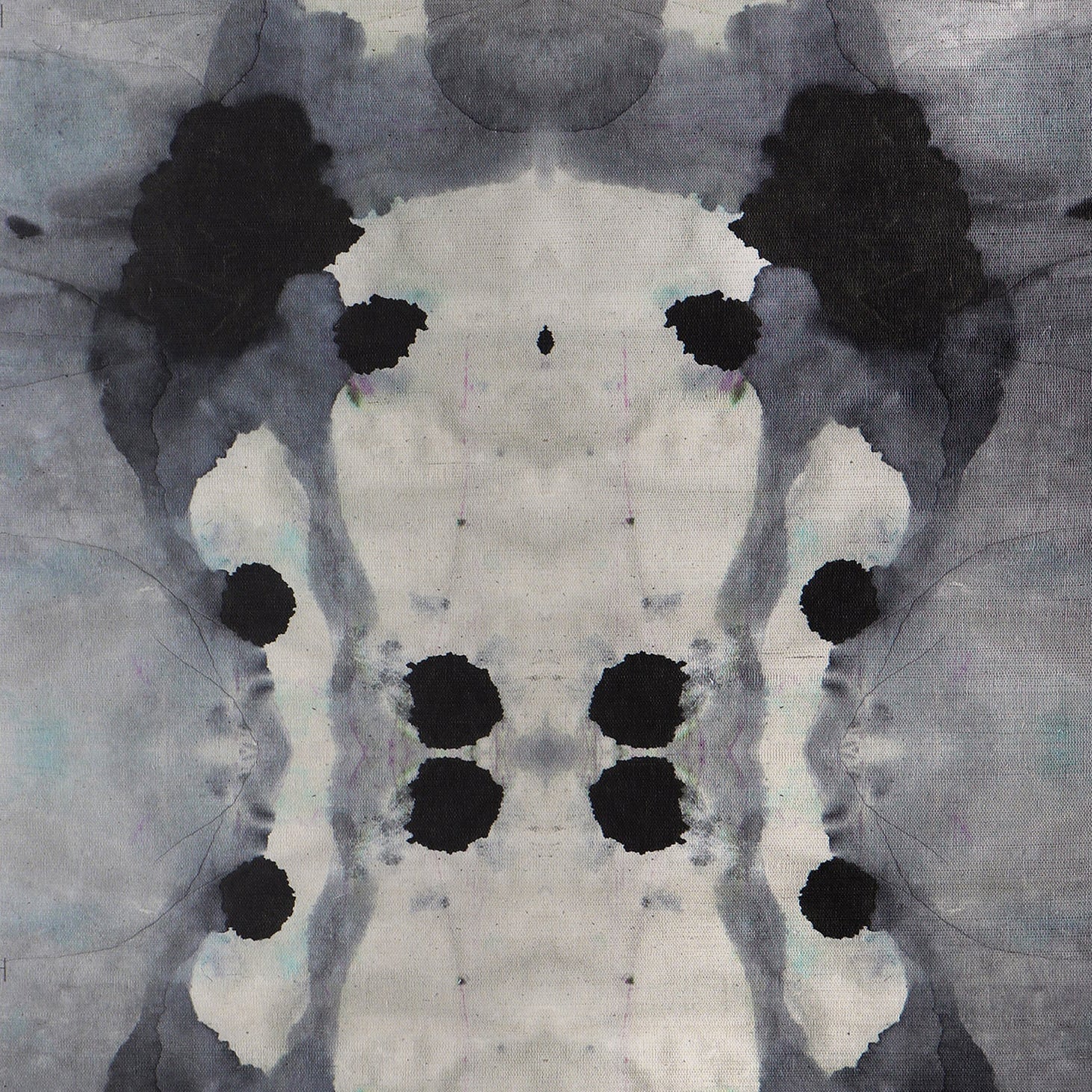Close-up of wallpaper in a watercolor ink blot print in shades of charcoal and gray on a tan field.