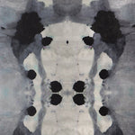 Close-up of wallpaper in a watercolor ink blot print in shades of charcoal and gray on a tan field.