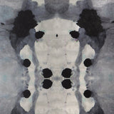 Close-up of wallpaper in a watercolor ink blot print in shades of charcoal and gray on a tan field.