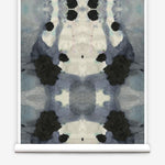 Partially unrolled wallpaper yardage in a watercolor ink blot print in charcoal, gray and tan.