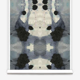 Partially unrolled wallpaper yardage in a watercolor ink blot print in charcoal, gray and tan.