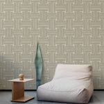 A plush chair and end table stand in front of a wall papered in a large-scale geometric print in tan and cream.
