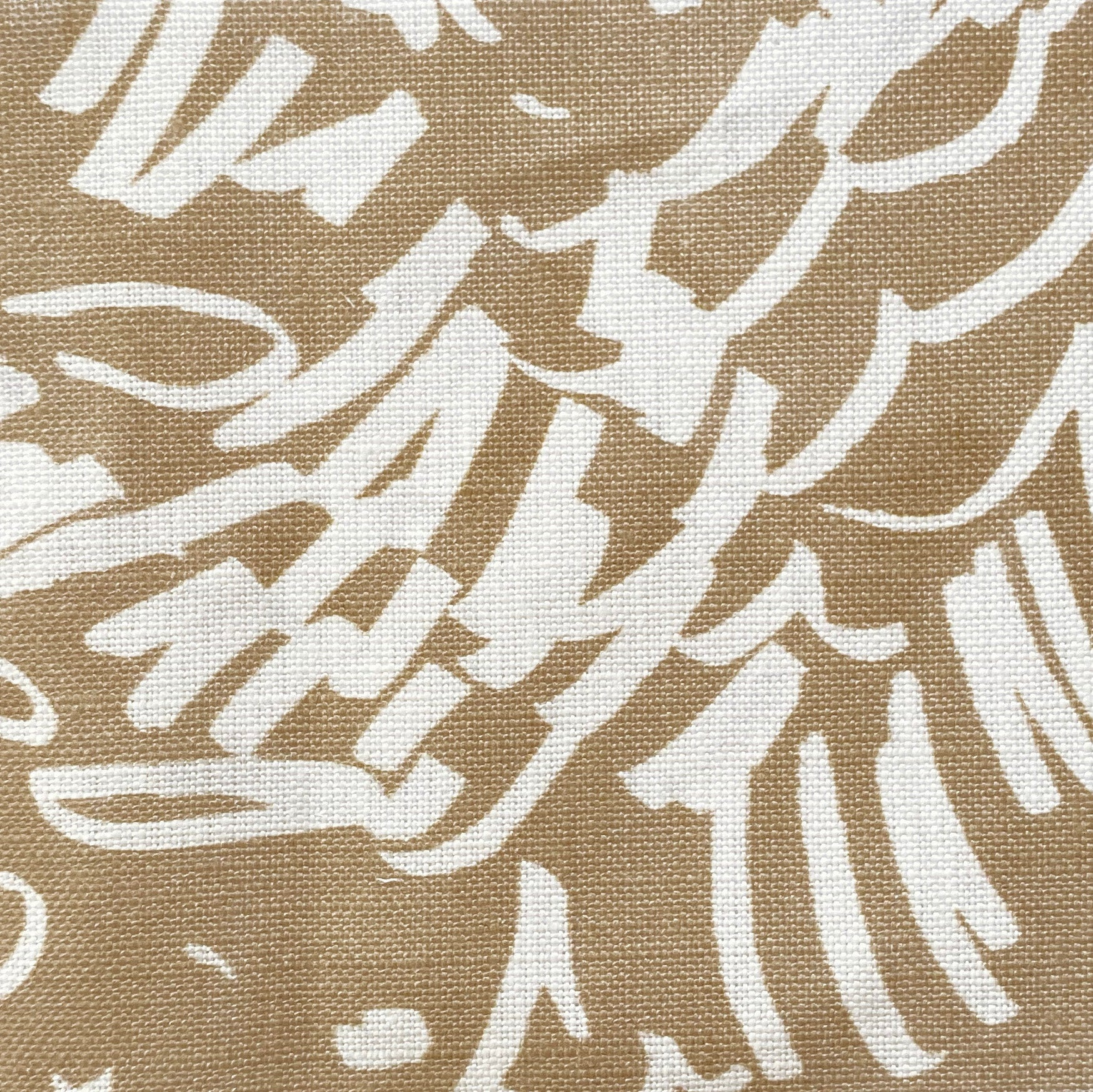 Close-up of fabric in a painterly wave print in white on a tan field.