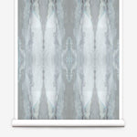 Partially unrolled wallpaper yardage in a watercolor textural print in shades of gray and blue-gray.
