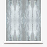 Partially unrolled wallpaper yardage in a watercolor textural print in shades of gray and blue-gray.