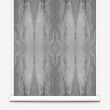 Partially unrolled wallpaper yardage in a watercolor textural print in shades of gray.