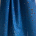 Draped fabric yardage in an abstract ombré paint splatter print in shades of blue and gray.