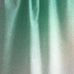 Draped fabric yardage in an abstract ombré paint splatter print in shades of turquoise, green and white.