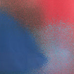 Detail of fabric in an abstract ombré paint splatter print in shades of blue, red and navy.