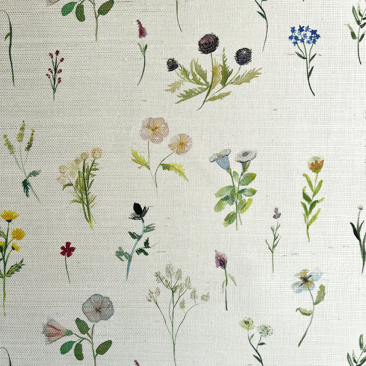 Detail of fabric in a painterly flower print in green and pastels on a cream field.
