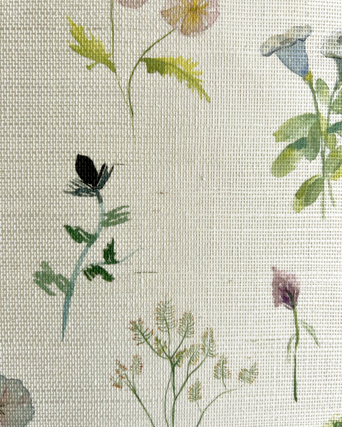Close-up of fabric in a painterly flower print in green and pastels on a cream field.