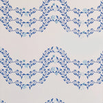 Detail of wallpaper in a curving floral stripe print in shades of blue on a cream field.