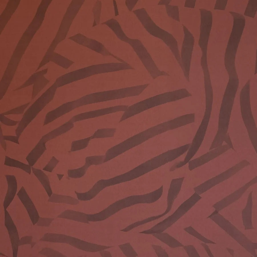 Detail of wallpaper in a playful broken stripe print in purple on a red field.