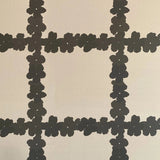 Detail of wallpaper in a floral grid print in brown on a white field.