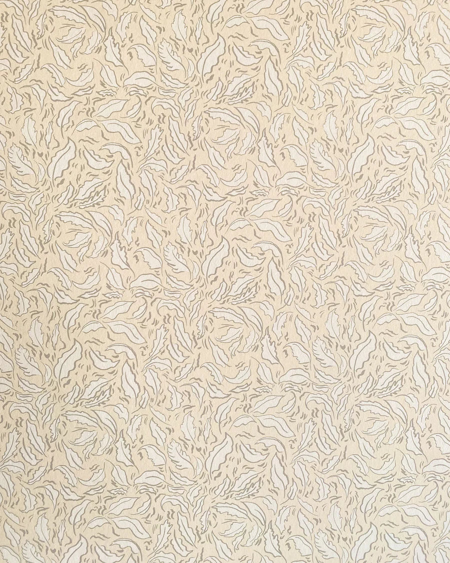 Detail of wallpaper in a painterly leaf print in tan and white on a cream field.